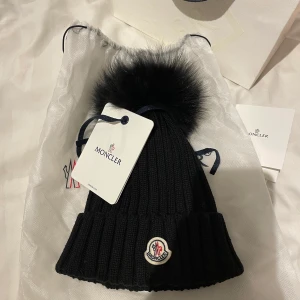 Moncler mössa - Använd ett få fal gånger, nästan som ny. Köpt för 2775kr, kivitto och äktenhetsbevis  finns kvar säljs tillsammans med allt som kom med vid inköp.