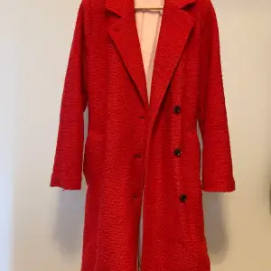 Lång kappa från SAMSOE   Färg: Röd med ljusrosa linning Material: 60% polyester, 40% ull Skick: Gott skick 