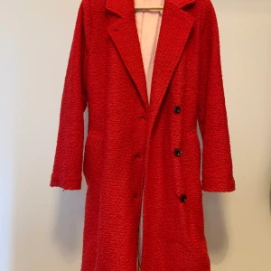 Vinterkappa SAMSOE SAMSOE - Lång kappa från SAMSOE   Färg: Röd med ljusrosa linning Material: 60% polyester, 40% ull Skick: Gott skick 