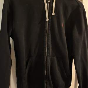 Äkta ralph lauren zip hoodie i storlek S. Använd men i gott skick. Bilder av sådär kvalitet, förtydligar att den är svart med ett mörkrött märke. 50kr+frakt