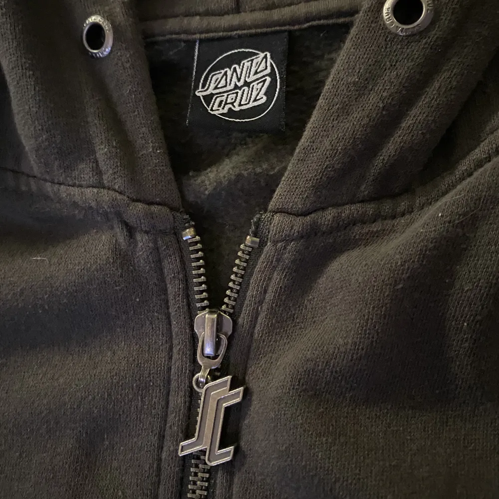 Zip-up hoodie ifårn santa cruz ifrån sent 90-tal, unik. Härlig passform i storlek L. Trots sin ålder har tröjan inga skador, endast snörerna saknas. Finns ett likadant tryck på ryggen. Färgen är typ brun/grön aktig.. Hoodies.