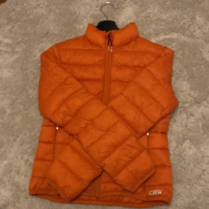 Orange CRW jacka - En sprillans ny orange CRW jacka, köpt på hööks för 449kr och säljes för 200kr!🥰 Jag råkade köpa i fel storlek. Jackan är i storlek 158/164! Aldrig använd. Passar perfekt nu till hösten! 🍂 Kan fraktas eller hämtas upp i Uppsala!🥰