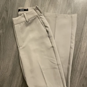 oanvända bikbok kostymbyxor - Helt oanvända bikbok kostymbyxor i strl 34! Grå/beige färg som inte längre säljs! Köptes i maj 2022. Trodde dom skulle komma till användning och därför är de insydda i midjan någon cm, men går att sprätta upp ifall man skulle vilja de. 240kr eller bud!