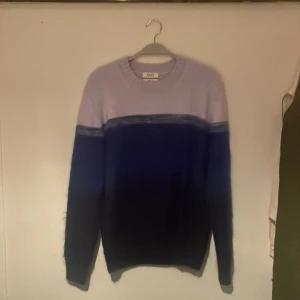 COS stickad tröja - Stickad tröja från COS!  Knappt använd tröja från COS, köptes våren 2021. Inga fläckar eller skador på tröjan. Tröjan är i tre nyanser av blå. Färgen på tröjan produceras ej längre.  Mått går att be om!  Stockholm