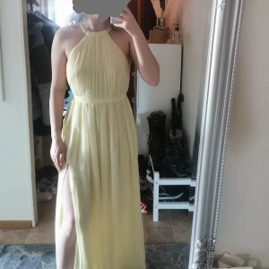 Balklänning - En fin gul bal eller bröllopsgäst klänning. Öppen rygg. Slits. Den sitter väldigt fint på. Jag är 166cm och den är perfekt längst på mig. Ändast använd 1 gång. Från NLY EVE