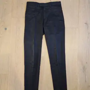 Ett par svarta och lätt blanka byxor från Filippa K med diskreta pressveck.  Storlek 44. Slim passform  Knappt använda.