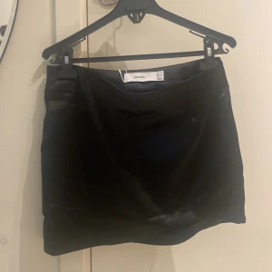 Svart minikjol - Väldigt fin minikjol i svart sidenmaterial, i storlek M. Helt omvänd med tag kvar!