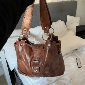 Väska - Stor rymlig väska i skinn. Dragkedjan funkar dock inte men finns spänne över