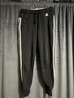 Adidas mjukisbyxor - Svarta adidas mjukisbyxor med vita detaljer. Använda flera gånger men fortfarande i bra skick. Resårbandet har blekts lite grann men inget man tänker på. Storlek XS. Pris kan diskuteras. Köparen står för frakten. Betalning sker via Swish.