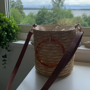 Liten väska - Liten väska från Newlook i strå, med både handtag och justerbart axelband. Använd någon gång bara, någon fläck på tyget men i övrigt väldigt gott skick. 