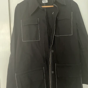 Lång svart workerjacka weekday XS  - Lång svart workerjacka jacka i kraftigt tyg med stora utanpåsydda fickor. Superfint skick som ny. 