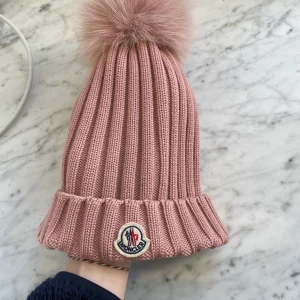 Moncler mössa - Jättefin gammalrosa mössa med fluffboll. Köpt på NK i Stockholm för ca 3000kr.