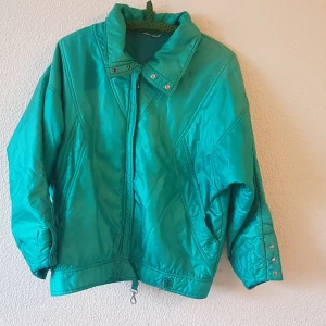 Vintage skidjacka från beyond retro - Snygg vintage skidjacka från beyond retro i glansig turkos färg. Märkt strl 42 men jag bedömer den som en M (herr) och L (dam). Sitter lagom oversize på mig som är strl 40. Den är fodrad men inte jättetjockt, så funkar fint även på höst eller tidig vår.