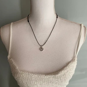 Egen gjort fint halsband - Det här är ett halsband som jag har gjort. Det är knutar som gör att man kan välja vilken storlek på halsband man vill ha. Berlocken är ett litet hjärta med blommor och blad runtomkring. Den är nickelfri.  Köparen står för frakten.  