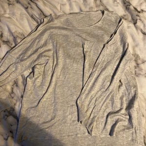 Tröja som visar axlarna  - En grå tröja med hål vid axlarna. Stl XL men skulle säga att den sitter bättre på L/mindre ändå
