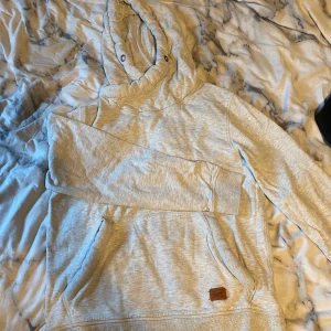 Hoodie - En grå hoodie från Jack & Jones. Tror det är en herrmodell men jag har haft den och tycker den sitter lika bra på båda. En stor ficka på magen