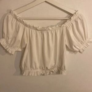 Topp med volang detaljer - Vit blus med volangdetaljer i ärmarna, urringningen och nertill. Passar perfekt till både byxor och kjol. Stl S från Gina Tricot. Köparen står för frakten🤍