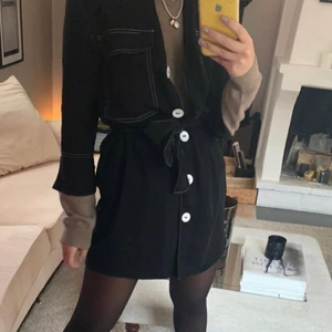 Svart klänning från zara - Första bilden är lånad. Svart klänning med vita sömmar och knappar. Band runt midjan medföljer. Köpt på Zara för typ 3 år sen, använd fåtal gånger. Fint skick! 