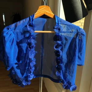 Kofta/bolero blå - Bolero kofta i blå med blomdetaljer. Vet tyvärr inte märket för den tillhörde min mamma, men skulle säga någon gammal turkisk märke. Storleken skulle jag uppskatta är S/M