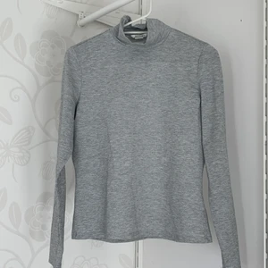 Monki Grå Topp M - Gråmelerad Monki topp i storlek. Tröjan har hög halsrigning och glittertrådar invävda i tyget (se sista bilden). Den passar inte mig längre så en bild på hur den sitter på mig kändes fel. 