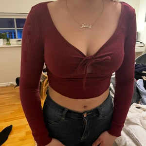 Vinröd topp - Säljer en vinröd topp med knytning i mitten.