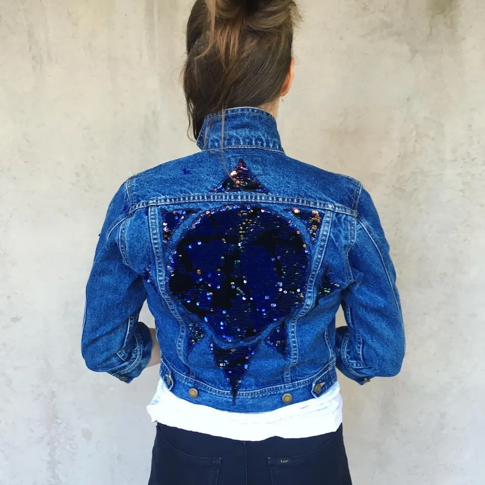 Reworked wrangles sport denim jacket. Flip sequin application in the shape of the sun and the moon and the stars. Also single sequins spread out on the left shoulder.   This jacket is a unique one of a kind find. Super cool and rad looking. You can choose to wear the sequins flipped down for the blue color or up to see the golden color.   Size S, Measurements:  Front length: 40 cm Shoulder: 13 cm Back length: 47 cm Back width: 45 cm Arm length outside: 46 cm Arm length inside: 36 cm. Jackor.