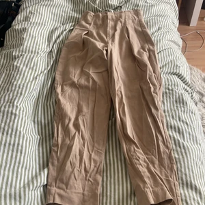 Kostymbyxor från Gina  - Ett par beiga kostymbyxor från Gina med form som ballong byxor. Använda 2 gången och sedan har jag aldrig använt dom mer. De är i storlek 32 och sitter bra på en! 
