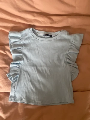 Blå zara topp - !!Har två!! Fin blå topp med volang detalj i utmärkt skick. Har även en i svart och en i vit