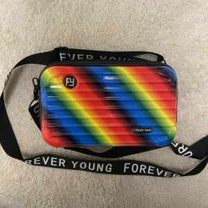 Regnbågsväska - Fin regnbågs väska från Kawaii. Finns två fack innuti och ett stort. Inga defekter. Säljer då den inte kommer till användning