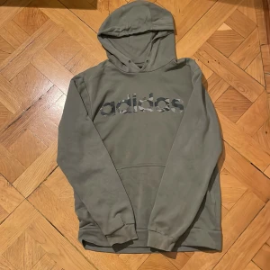 Grön/Oliv Adidas tjocktröja hoodie - Begagnad Adidas tjocktröja/hoodie med luva. Bra skick, inga fläckar dock finns inte snörena kvar. Small, passar barn 11-15