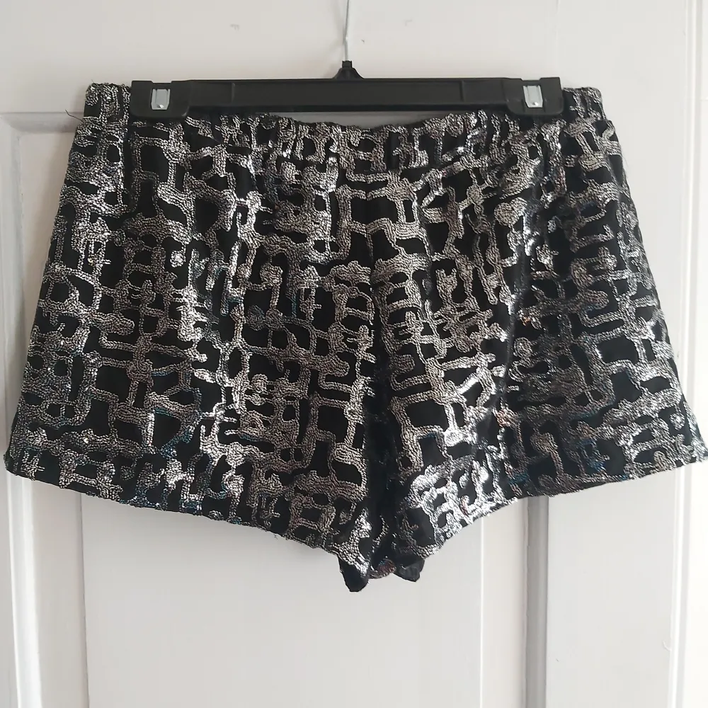 Svarta minishorts med silverglittrigt mönster med fickor från Urban Outfitters (strl M). Shorts.