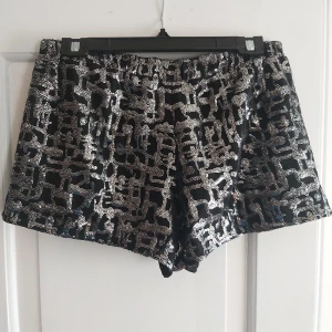 Party shorts - Svarta minishorts med silverglittrigt mönster med fickor från Urban Outfitters (strl M)
