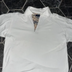 Burberry pike  - Burberry piké  Storlek: 14 kids men sitter som en small  Superfint skick förutom en liten fläck på magen, går att bleka bort men har inte orkat ta tag i det!