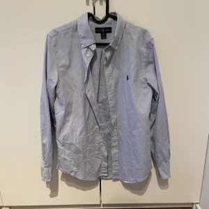 Ralph Lauren skjorta - Jag säljer en blå Ralph Lauren skjorta i bra skick. Storlek: 18 år men är liten i storleken så skulle säga att den är S/M. Pris: 200kr.