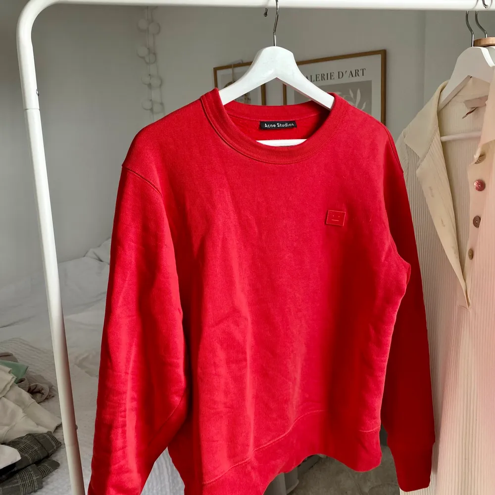 Acne studios sweatshirt i en klar röd färg med den klassiska smileyn. Använd fåtal gånger, väldigt fint skick. Hoppas någon annan kan använda den mer. 😌  Storlek XS unisex, oversize modell. Nypris 2400 kr. Tröjor & Koftor.