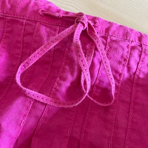 Kort kjol - Rosa, kort, linnekjol med rosett på framsidan🌸 Har både dragkedja på sidan och 1 knapp. 