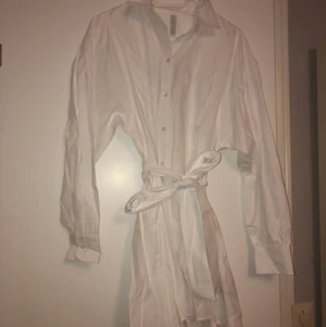 Vit klänning - Vit skjorta klänning med knappar och snörning framtill.