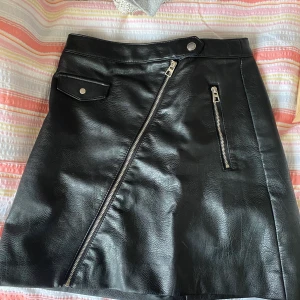 Svart läderkjol  - Säljer en svart fake läderkjol från HM. Använd två gånger. Lite alinje modell. Sitter hödmidjad. Nypris :250kr 