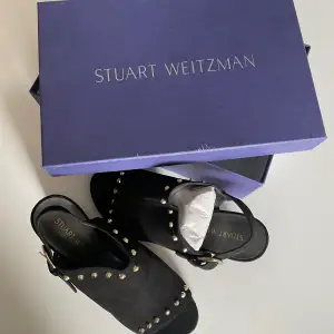Oanvända klackar från Stuart Weitzman. Läder. Svarta med guldiga nitar 