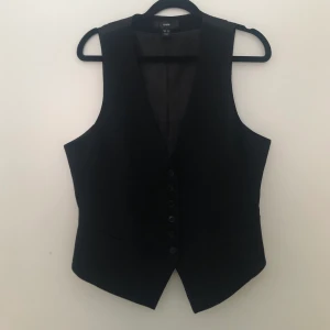 Kostymväst strl 42 - En dam kostymer från H&M i perfekt skick med funktionstangenter fickor och stabila knappar. Storlek 42 och midjemått på 94cm. Köparen står för frakt och ingen bild på finns:(