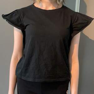 En svart t-shirt/ top med puffiga ärmar (nästan volangaktiga) 