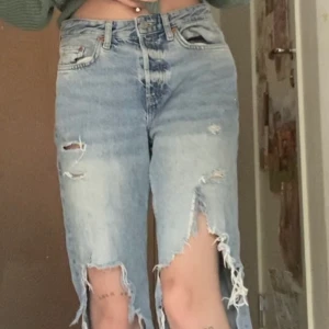 boyfriend jeans, low- waist - ett par jeans med stora hål över knäna, har haft dem länge så dem är ganska slita och har en regnbåge målad med akrylfärg på ena bakfickan.
