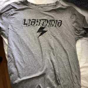 En grå T-shirt från Lager 157 i storlek M med texten Lightning på framsidan.