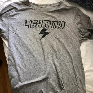 Grå T-shirt i storlek M. - En grå T-shirt från Lager 157 i storlek M med texten Lightning på framsidan.