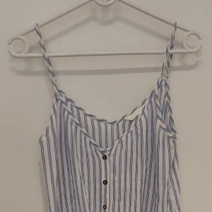 Vit- och blårandigt linne från HM med knyt fram - Superfint linne i skönt tyg. Material 100% viskos. Använt 2 gng men är lite för liten för mig tyvärr.