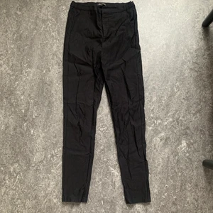 Svarta högmidjade byxor storlek M - Svarta högmidjade byxor i storlek M. Midjan är stretchig och de stängs med dragkedja och knapp. Frakt tillkommer. 