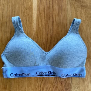 Bh från Calvin Klein - Skön bh för både dag och natt! Grå med vitt band, som tyvärr blivit något missfärgat åt det blå/gråa hållet med tiden. Väldigt skön men tyvärr för liten för mig med 75D/E i kupa. Storlek s!