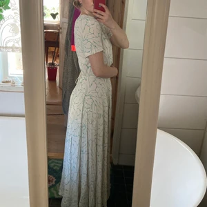 Vit maxiklänning strl 36 - Enkel och elegant vit maxiklänning med turkosa detaljer! Den kommer från HM och är använd ett fåtal gånger. Knytband bak i midjan! 