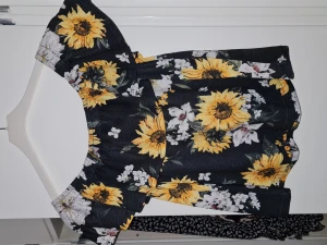 Tröja - Svart of shoulder tröja med solrosor från Gina. Storlek XS