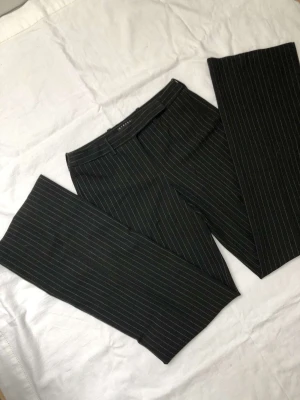 Kostymbyxor  - Lågmidjade, långa, randiga, svarta kostymbyxor, från märket sisley, passar till 34-38, ser väldigt fint ut på